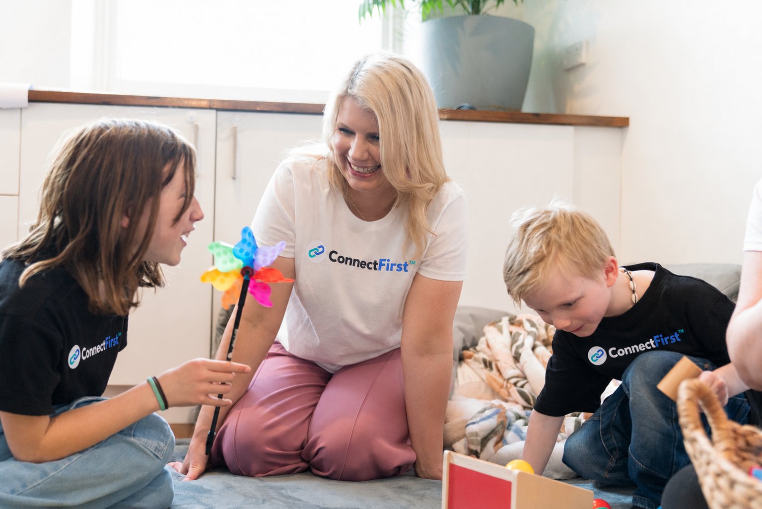 Meg Hughes playing on the floor with two children